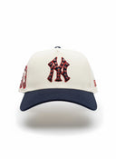 Gorra New Era 9Forty A-Frame NY Yankees de One Kickz en color crema y azul marino con cristales rojos en el logo.