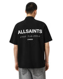 Hombre de espaldas vistiendo polo negro oversized AllSaints con logo Underground y texto en japonés en la espalda