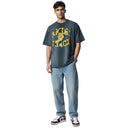 Hombre vistiendo camiseta negra lavada One Kickz Amiri con logo amarillo Track y zapatillas deportivas