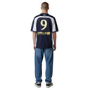 Hombre de espaldas vistiendo camiseta de fútbol One Kickz azul y blanca con el número 9 y logo Off-White en algodón