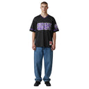 Modelo vistiendo camiseta de fútbol One Kickz Supreme Mitchell & Ness negra con letras moradas y cuello en V