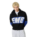 Modelo con chaqueta de punto negra con cremallera Eme Studios Thrill Sodalite R9, logo blanco y azul, One Kickz