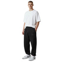 Modelo vistiendo pantalones de chándal negros Corteiz Alcatraz Triple Black con camiseta blanca y zapatillas