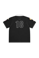 Camiseta polo negra Corteiz Alpine con cuello blanco, numero 18 en la espalda y parches detallados en las mangas
