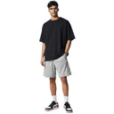 Modelo vistiendo pantalones cortos deportivos grises Corteiz Dem Pro de One Kickz con camiseta negra y zapatillas