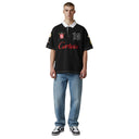 Modelo vistiendo polo One Kickz Corteiz Alpine negro con cuello blanco, bordados deportivos y corte oversize.