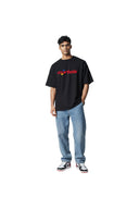 Modelo vistiendo camiseta negra Corteiz Stars con logo colorido, jeans azules y zapatillas One Kickz