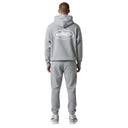 Hombre de espaldas vistiendo sudadera con capucha One Kickz Corteiz Island gris jaspeado con logo estampado en relieve